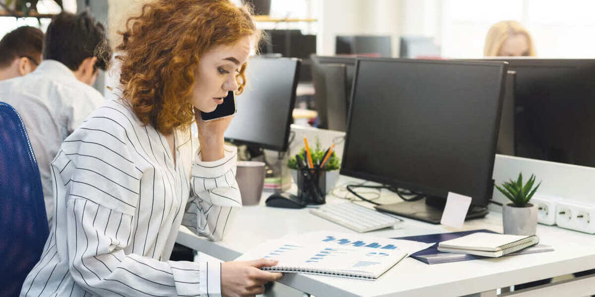 Woman looking at presentation while on the phone at a desk